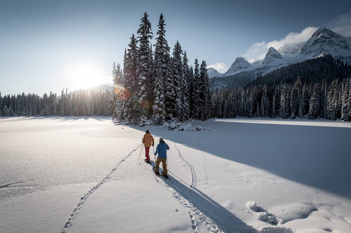 A couple snowshoeing in old growth forest at Island Lake Lodge