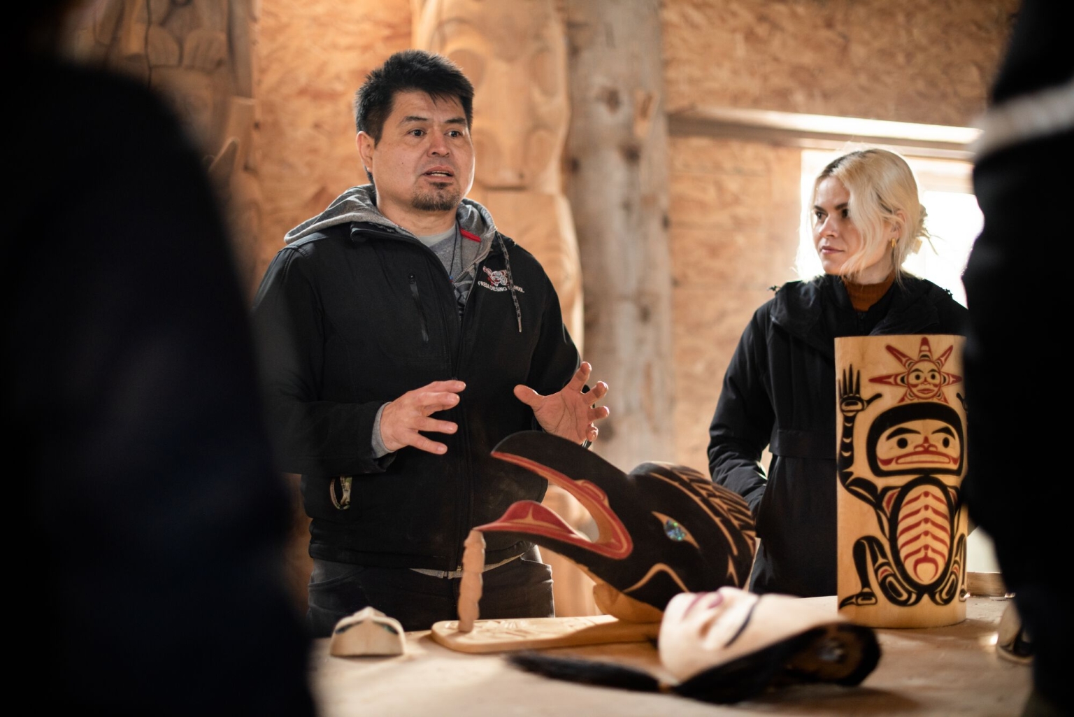 Indigenous artist Calvin McNeill stands in front of art pieces sharing more about history and culture of the Nisga'a People.