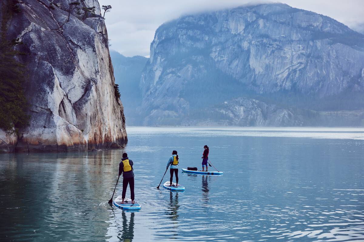 Three paddleboarders surrounded by massive rocks.