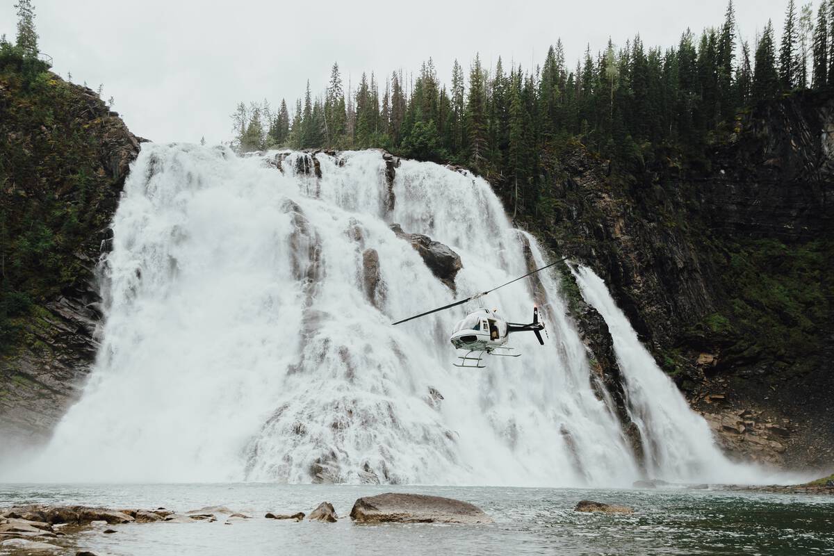 A helicopter flies low beside the spectacular 70-metre high Kinuseo Falls..