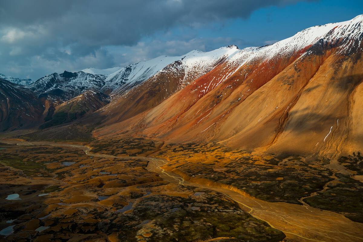 Snow covers the peaks of rust-coloured mountains in Mount Edziza Provincial Park.