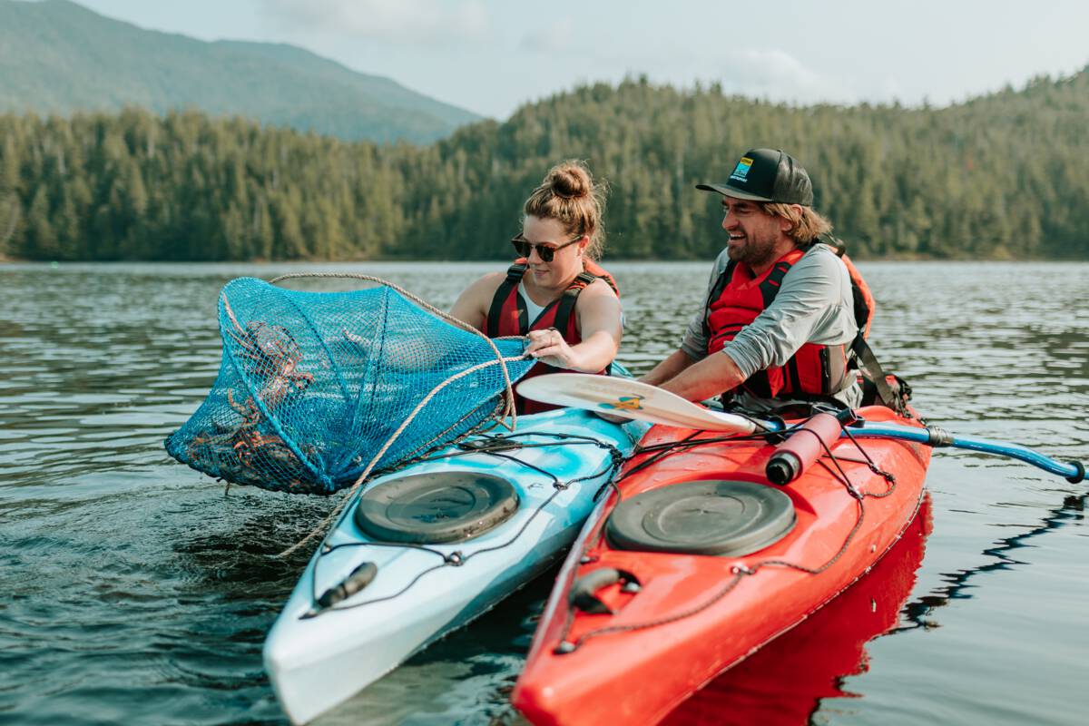 Two people in kayaks haul up a net filled with crabs.