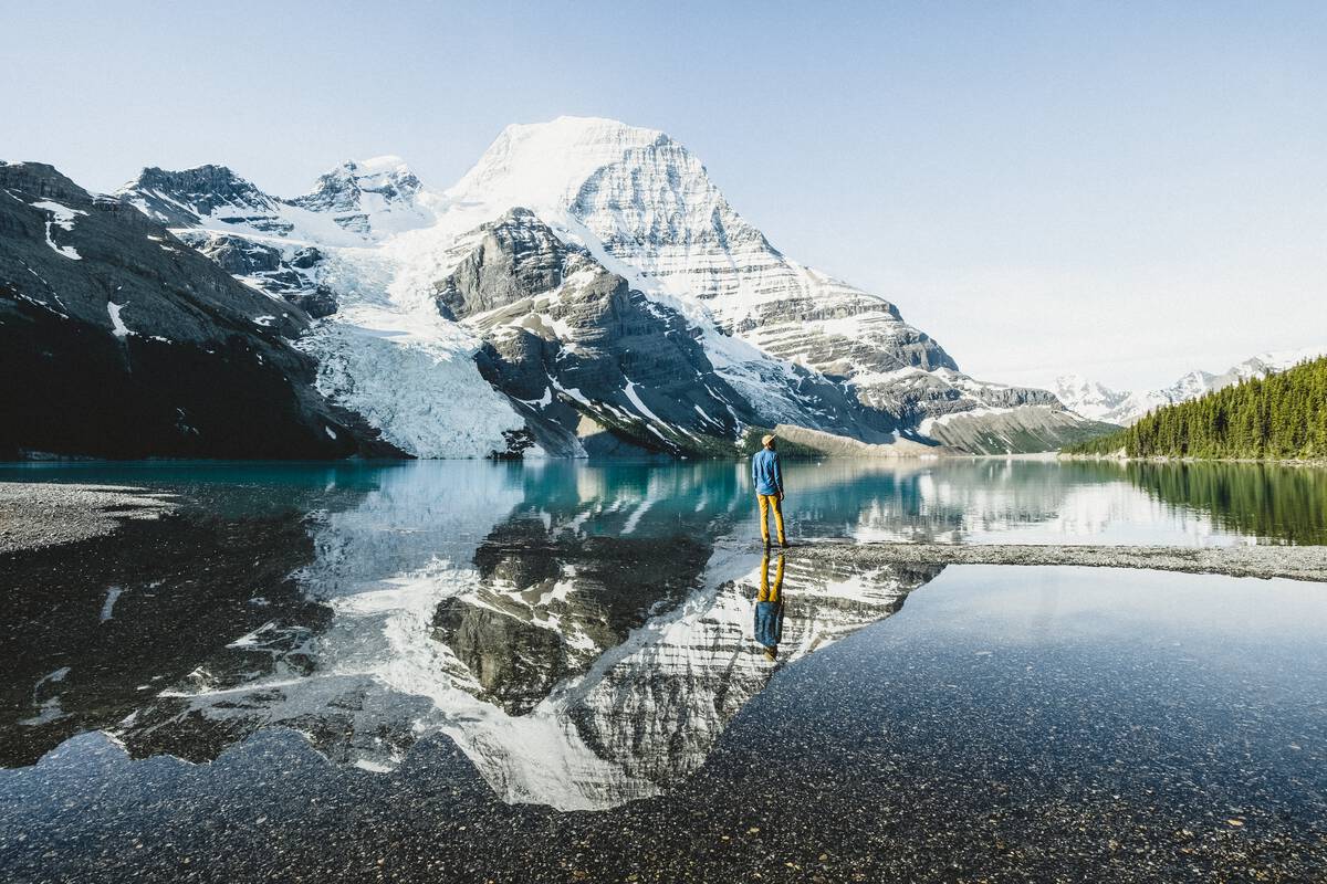 A person looks in awe at the layered mountain flanks of Mt. Robson.