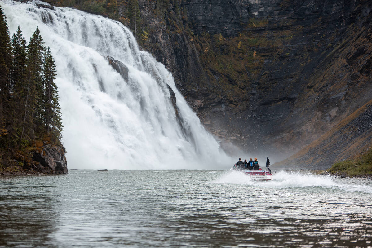 A jet boat approaches a cascading waterfall that towers over 70 metres high.