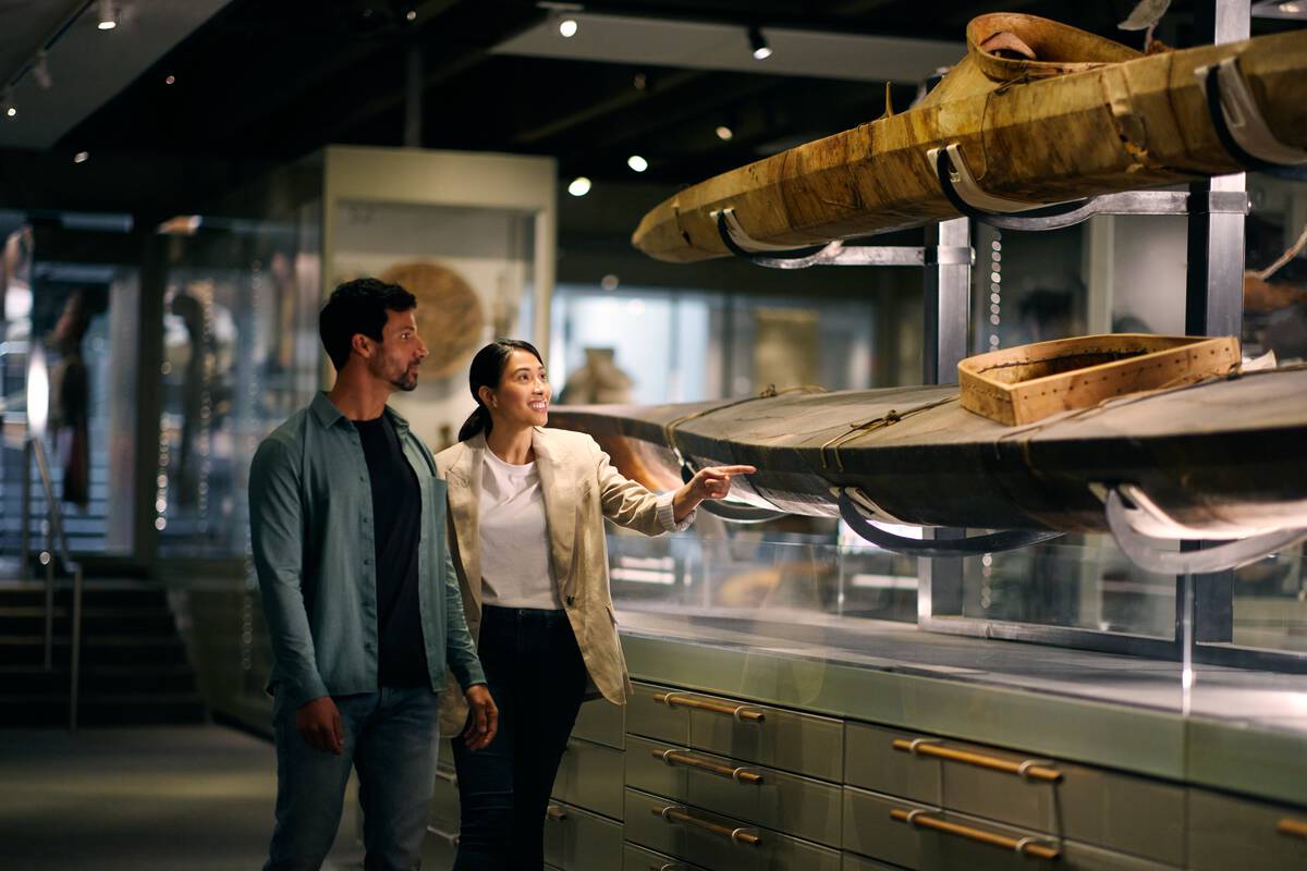 A couple walking along a corridor that features a long canoe.