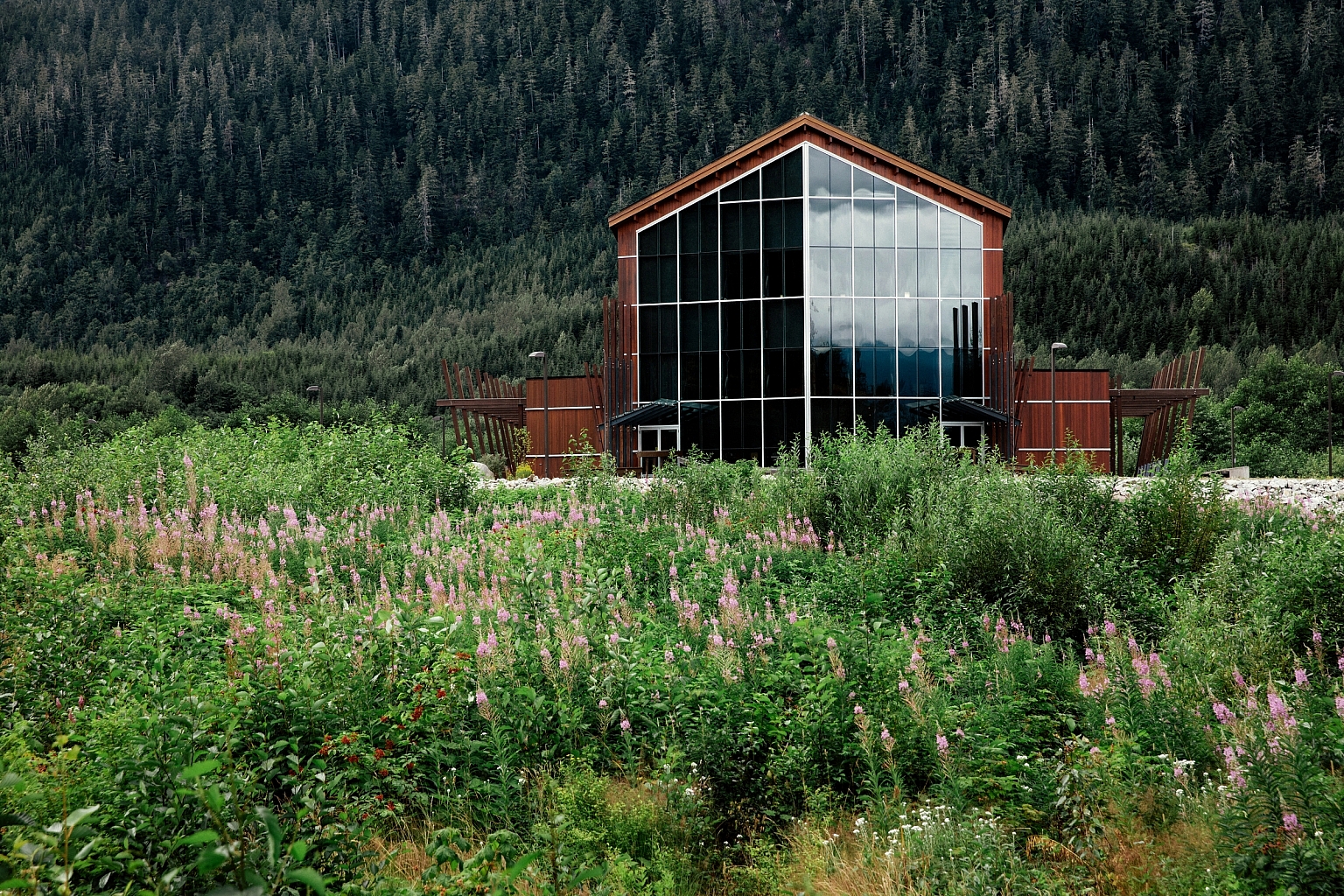 The Nisga'a Museum in Village of Laxgalts'ap, Nisga'a Nation is a beautifully designed wooden building with large floor to ceiling windows, perched in a lush forest.